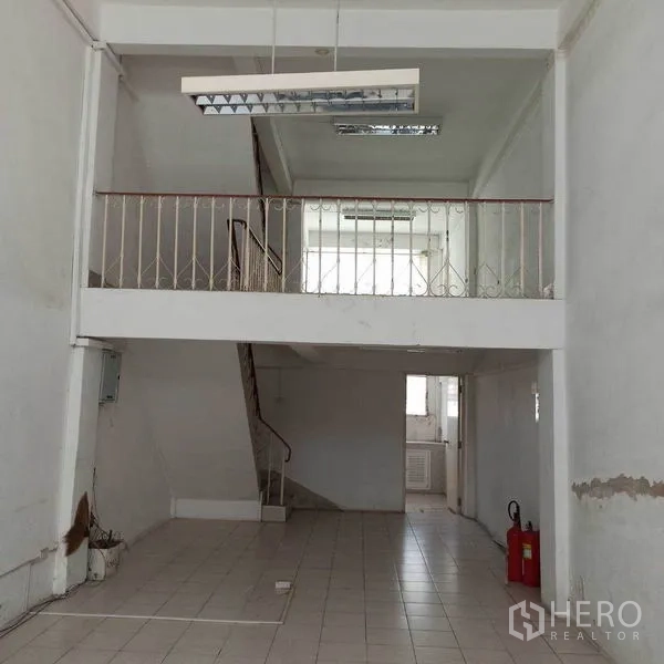 Shophouse for rent in Khlong Toei, Bangkok - Double-height front area with mezzanine, tiled floor and fire extinguisher.