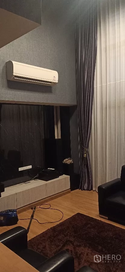 Detached House for rent or sale in Khan Na Yao, Bangkok - Media corner with wall-mounted A/C, TV console and dark drapes.