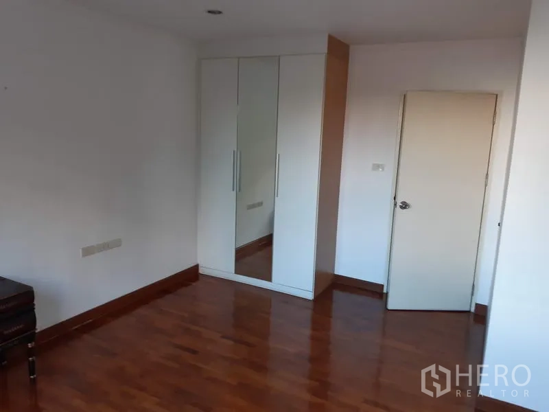 公寓 出售在Watthana, Bangkok - 卧室一角的白色镜面衣柜与木地板。