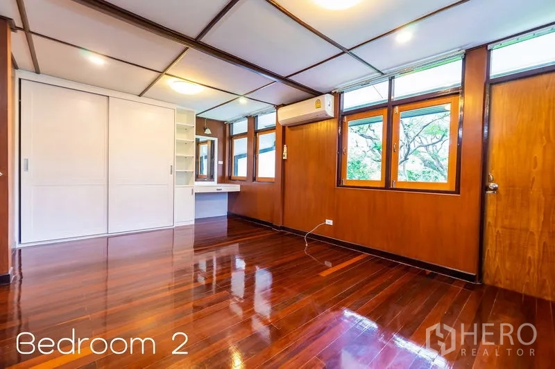 Detached House for rent in Huai Khwang, Bangkok - Bright wooden bedroom with glossy floors, built-in wardrobe and air conditioning.