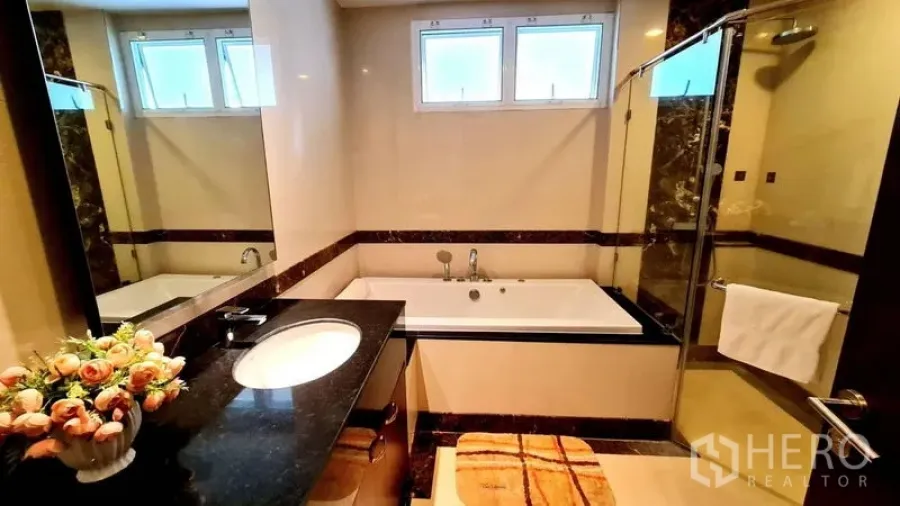 Apartment for rent in Khlong Toei, Bangkok - Modern bathroom with soaking tub, glass shower and stone vanity in a Phrom Phong apartment.