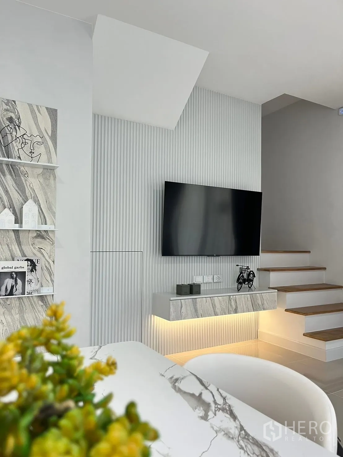 Townhouse for rent in Bang Phli, Samut Prakan - TV wall with floating console, warm accent lighting, and a staircase in a modern townhouse.
