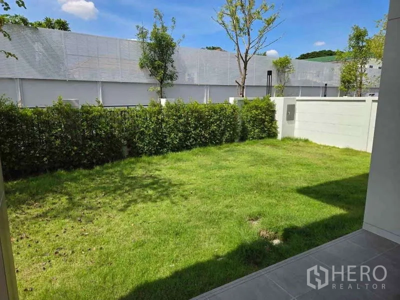 Detached House for rent in Bang Phli, Samut Prakan - Private backyard lawn bordered by hedges and a white privacy wall.