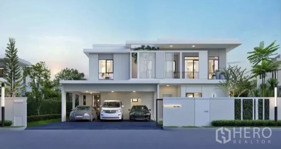 Detached House for rent in Samut Prakan - Modern two-storey detached house facade with large windows, landscaped greenery and a covered triple carport.
