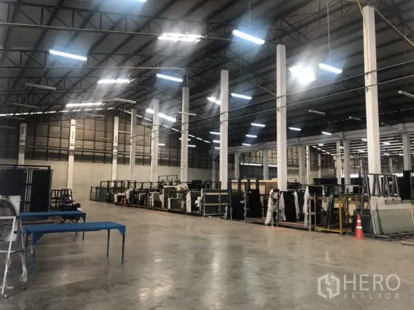 货栈 出租在Nonthaburi - 仓库内部，高挑钢结构屋顶、白色立柱与LED照明