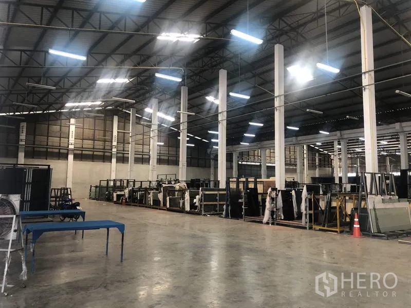 货栈 出租在Nonthaburi - 仓库内部，高挑钢结构屋顶、白色立柱与LED照明