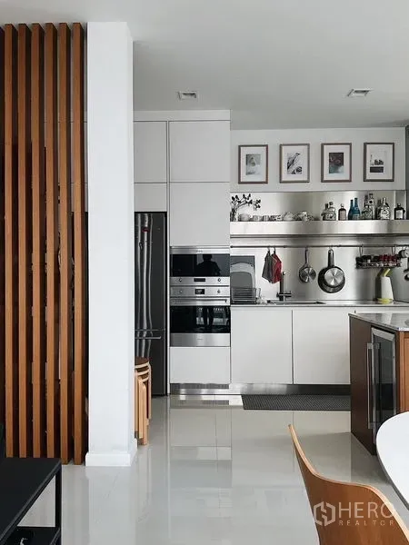 Detached House for sale in Bang Kapi, Bangkok - Sleek white kitchen with built-in ovens, open shelving, and a vertical wood divider.