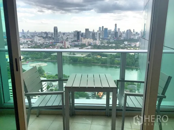 公寓 出租在Khlong Toei, Bangkok - 高楼层阳台配桌椅，俯瞰班加奇蒂公园湖与曼谷天际线。