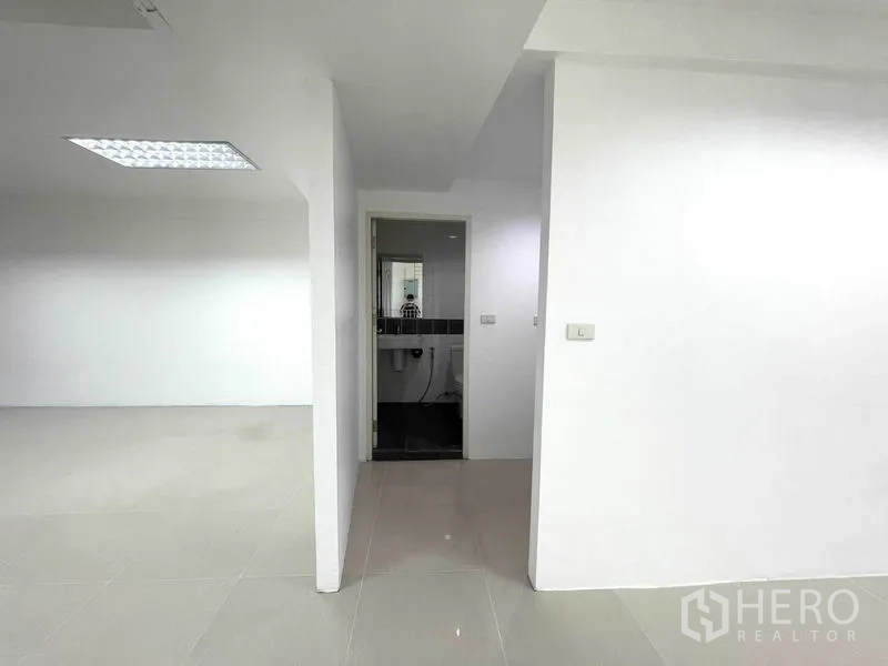 办公空间 出租在Khlong Toei, Bangkok - 从开放办公区进入的卫生间入口，白色隔墙。