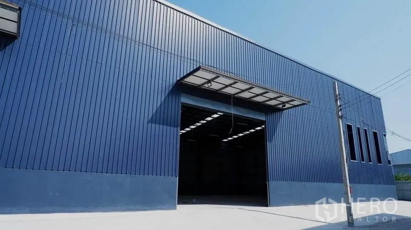 Warehouse for rent in Bueng Kum, Bangkok - Blue metal-clad warehouse exterior with wide loading entrance and canopy.