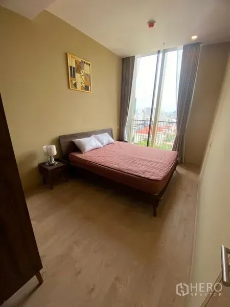 Condominium for rent in Watthana, Bangkok - Bright bedroom with double bed, wood floors and floor-to-ceiling windows.