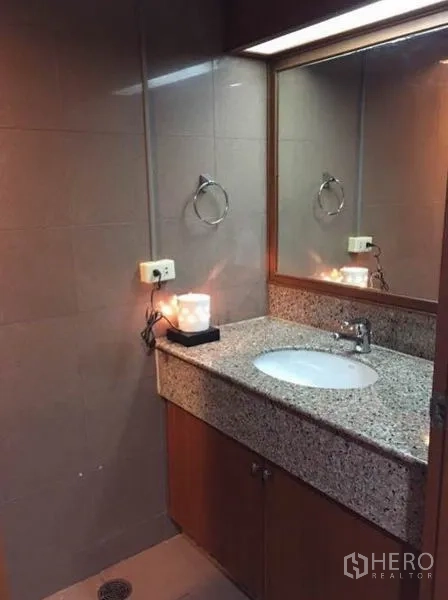 Condominium for rent or sale in Watthana, Bangkok - Second bathroom with stone vanity, mirror and tiled walls.