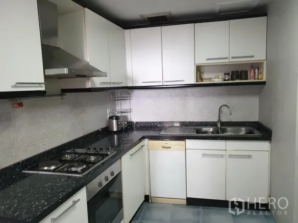 Condominium for rent in Khlong Toei, Bangkok - U-shaped kitchen with granite countertops, gas hob, oven, range hood, dishwasher and double sink.