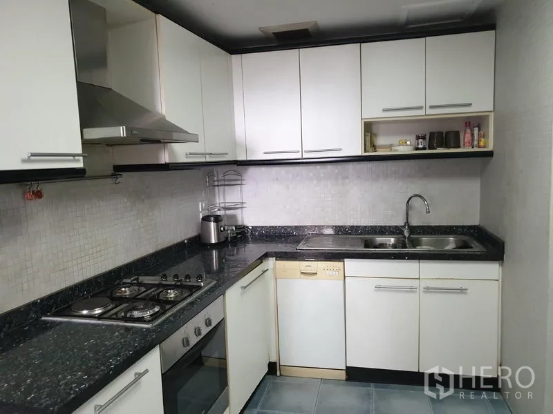 Condominium for rent in Khlong Toei, Bangkok - U-shaped kitchen with granite countertops, gas hob, oven, range hood, dishwasher and double sink.