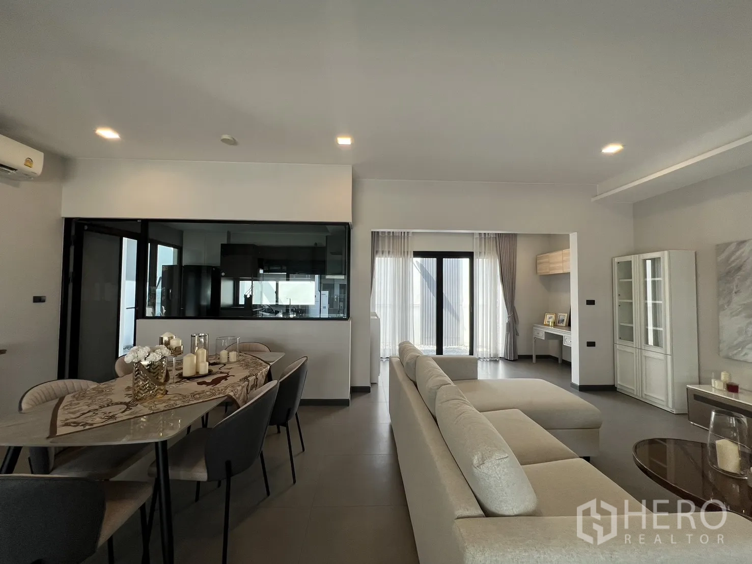 Detached House for rent in Bang Phli, Samut Prakan - Dining area beside a glass-enclosed kitchen and terrace doors with curtains.