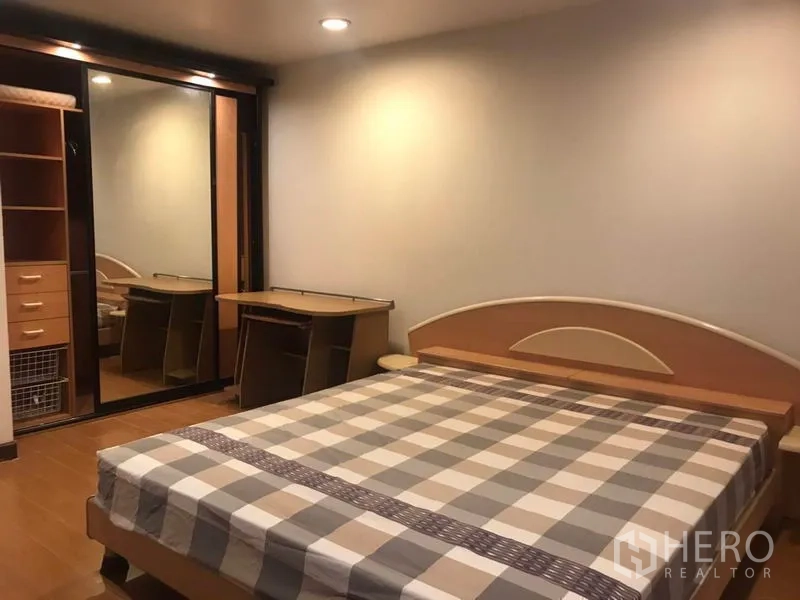 Condominium for rent or sale in Khlong Toei, Bangkok - Master bedroom with mirrored wardrobe and built-in desk.