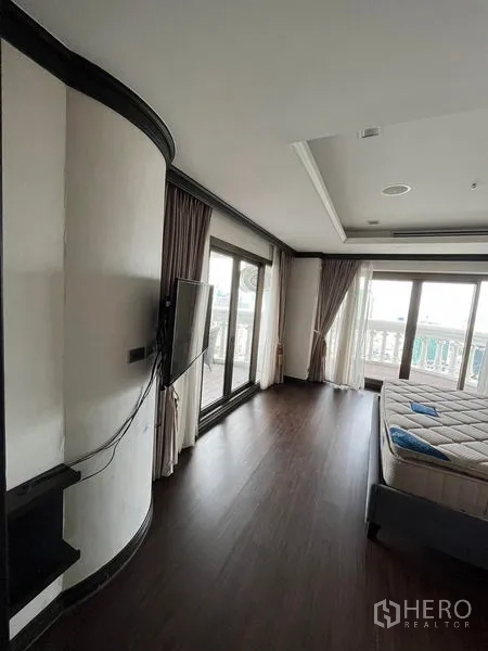 公寓 出售在Bang Rak, Bangkok - 次卧，深色木地板、弧形墙面并直通阳台。