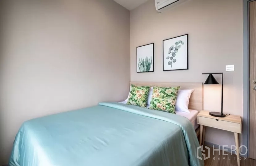 Condominium for rent in Chatuchak, Bangkok - Second bedroom with bedside lamp, framed prints and neatly made bed.