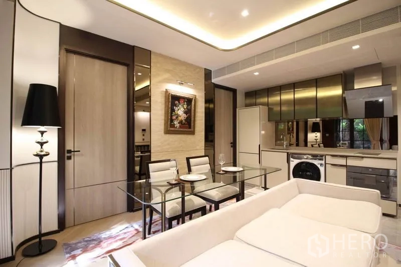公寓 出租在Watthana, Bangkok - 现代起居空间，沙发、黑色落地灯与天花灯带，邻近厨房。