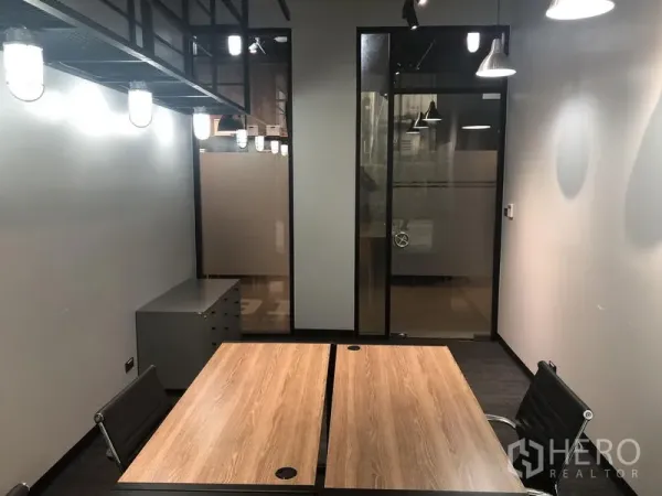 Office Space for rent in Khlong Toei, Bangkok - Private serviced office with two wooden desks, black chairs, frosted glass door and industrial pendant lighting.