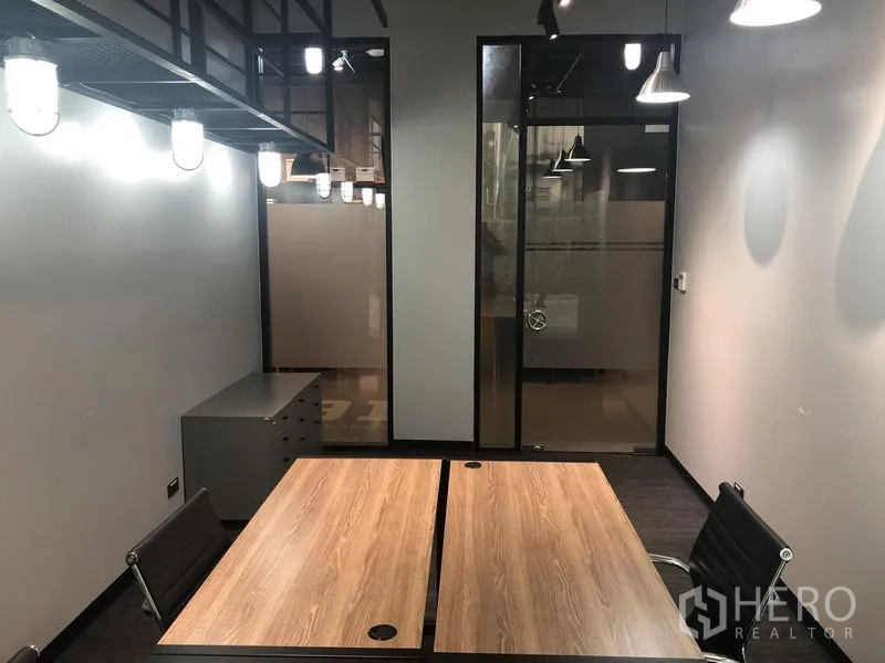 Office Space for rent in Khlong Toei, Bangkok - Private serviced office with two wooden desks, black chairs, frosted glass door and industrial pendant lighting.
