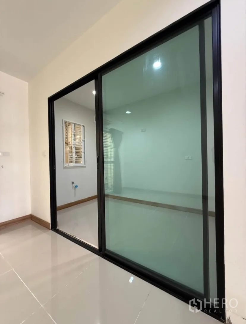 Townhouse for rent in Suan Luang, Bangkok - Glass sliding partition separating a multipurpose room from the living area.