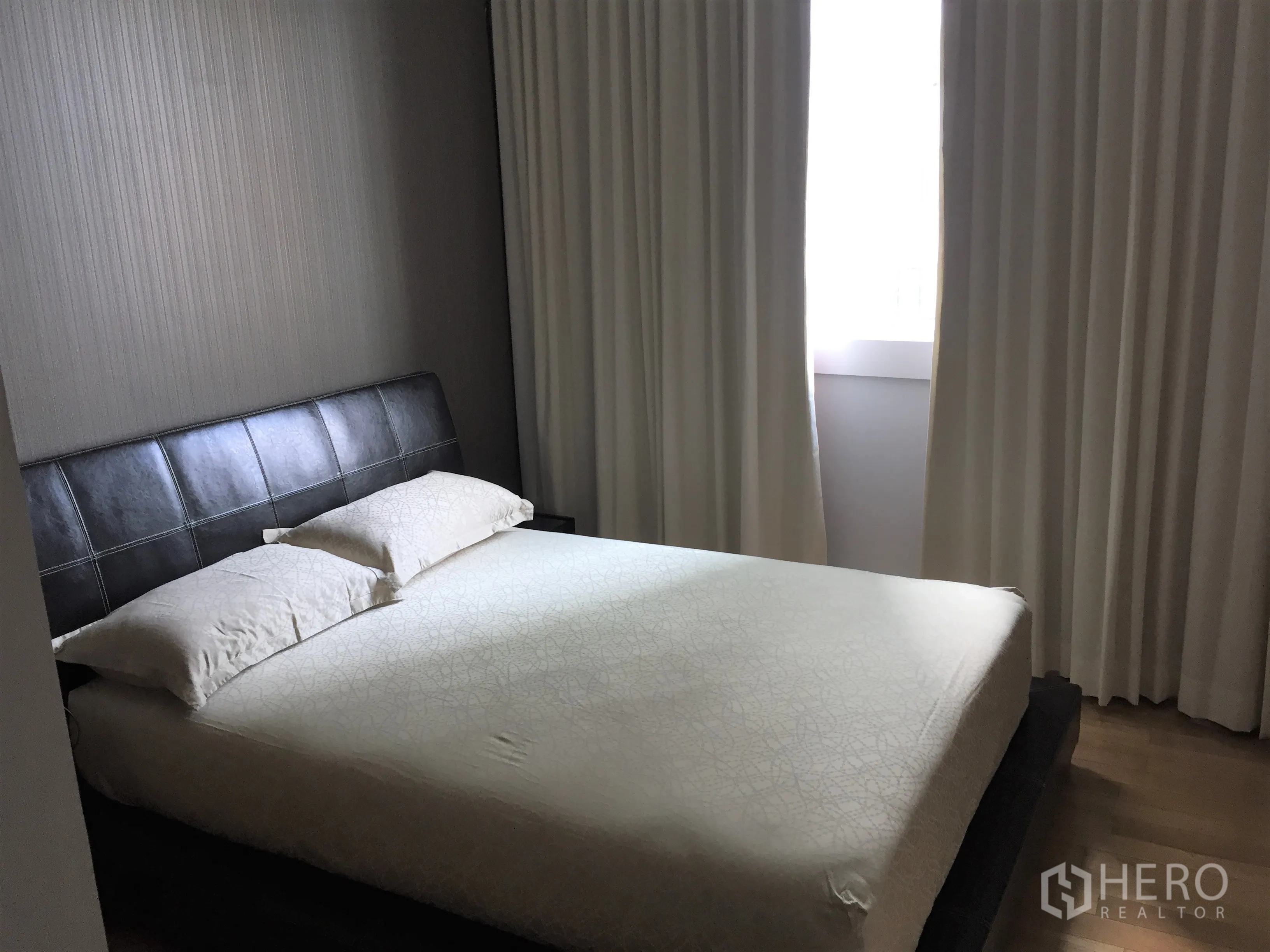Condominium for rent or sale in Khlong Toei, Bangkok - Guest bedroom with leather headboard, blackout curtains and soft natural light.