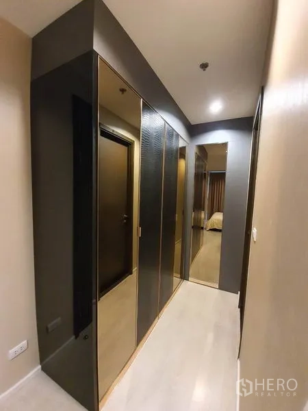 公寓 出租在Sathon, Bangkok - 更衣走廊，顶天立地镜面衣柜与浅色木地板。