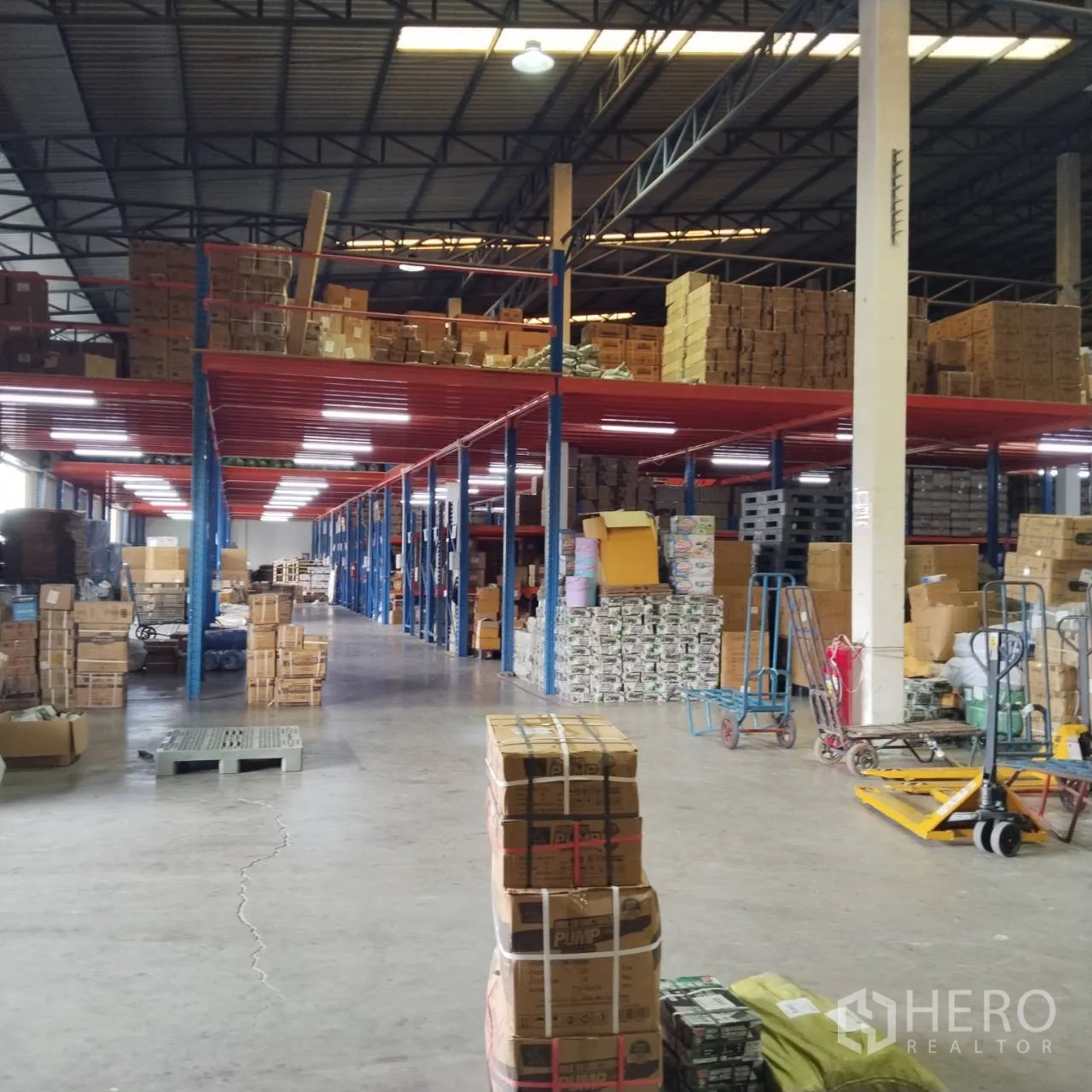 Warehouse for rent in Bang Khun Thian, Bangkok - Spacious warehouse zone with steel roof trusses and mezzanine shelving.