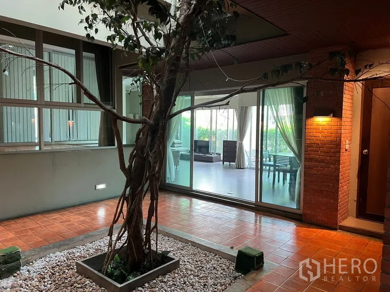 อพาร์ทเมนท์ ให้เช่าในWatthana, Bangkok - ลานกลางบ้านมีต้นไม้ กระบะหินกรวด และประตูกระจกเลื่อนเชื่อมสู่ห้องนั่งเล่น