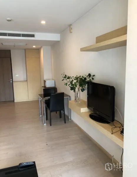 公寓 出租在Khlong Toei, Bangkok - 电视置于壁挂层板旁，配两人餐桌与浅色木地板