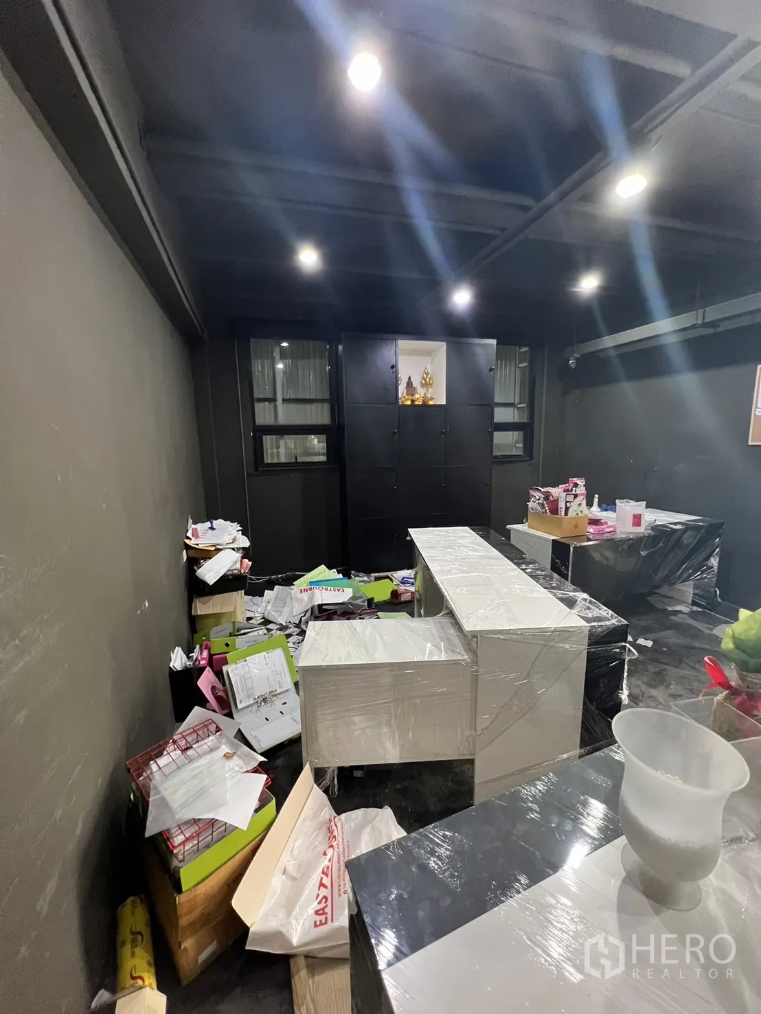 Shophouse for rent in Watthana, Bangkok - Compact office or storage room with dark walls, cabinets and scattered paperwork.