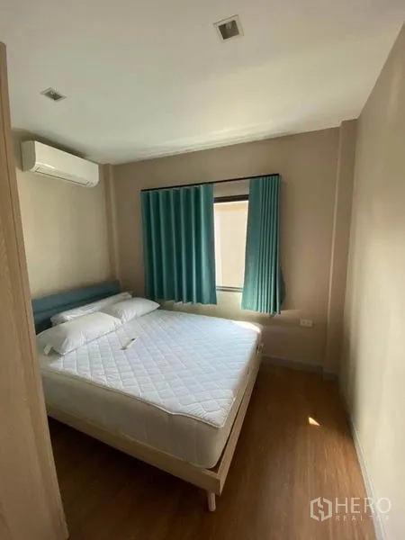 Detached House for rent or sale in Saphan Sung, Bangkok - Sunlit bedroom with double bed, teal curtains and air conditioner.