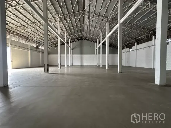 Warehouse for rent in Phra Khanong, Bangkok - Polished concrete floor warehouse space with tall columns and a roller door at the end.