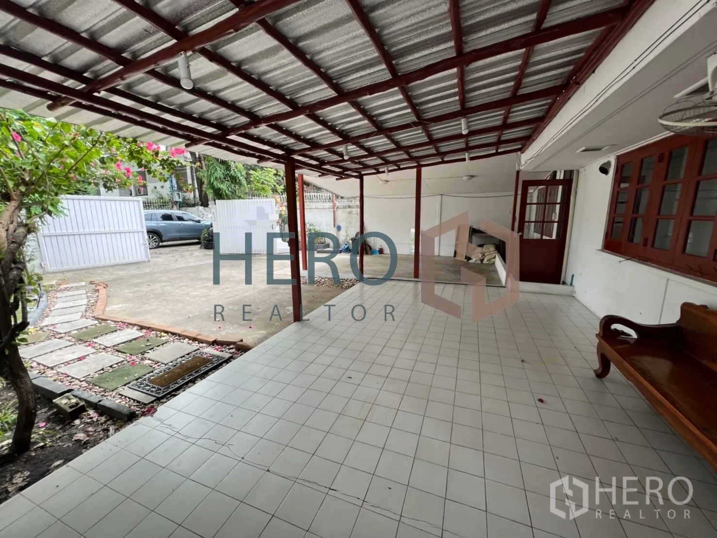 独立式住宅 出租在Watthana, Bangkok - 带顶棚的铺砖车棚与前廊，配木长椅