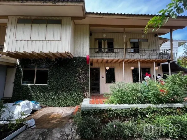 Townhouse for rent - Two-storey wooden townhouse facade with ivy-clad wall, balcony and front garden.