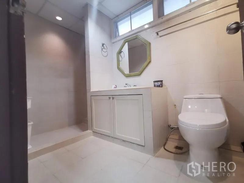 Apartment for rent in Khlong Toei, Bangkok - Secondary bathroom with walk-in shower, octagon mirror, vanity and window.