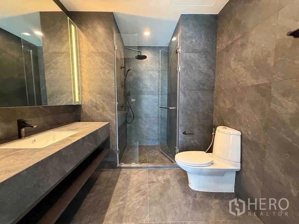 คอนโด for rent in Ratchathewi, Bangkok - ห้องน้ำกว้างปูกระเบื้องหินสีเทา พร้อมตู้กั้นอาบน้ำกระจก เคาน์เตอร์ยาว และโถสุขภัณฑ์