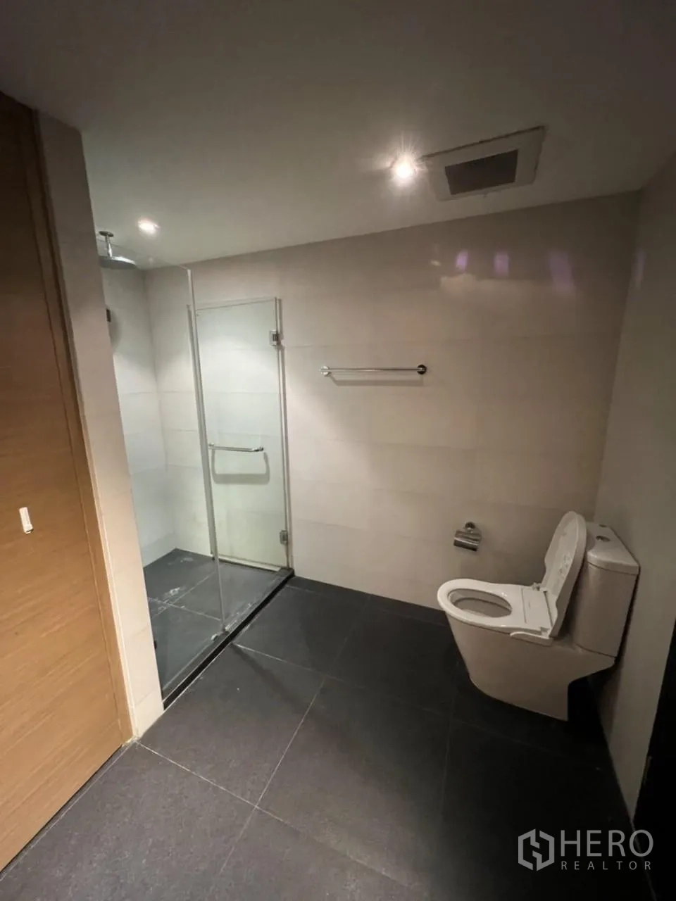 公寓 出租在Watthana, Bangkok - 淋浴间配玻璃围隔、顶喷花洒、筒灯与深色地砖。