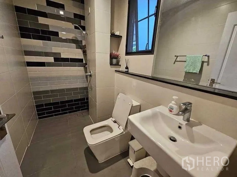 Detached House for sale in Bang Kruai, Nonthaburi - Contemporary bathroom with walk-in shower, striped wall tiles, window, toilet and sink.