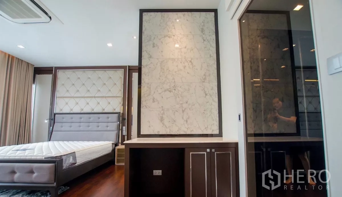 独立式住宅 出租在Bang Bon, Bangkok - 卧室一角，带大理石装饰墙与步入式衣帽间入口。