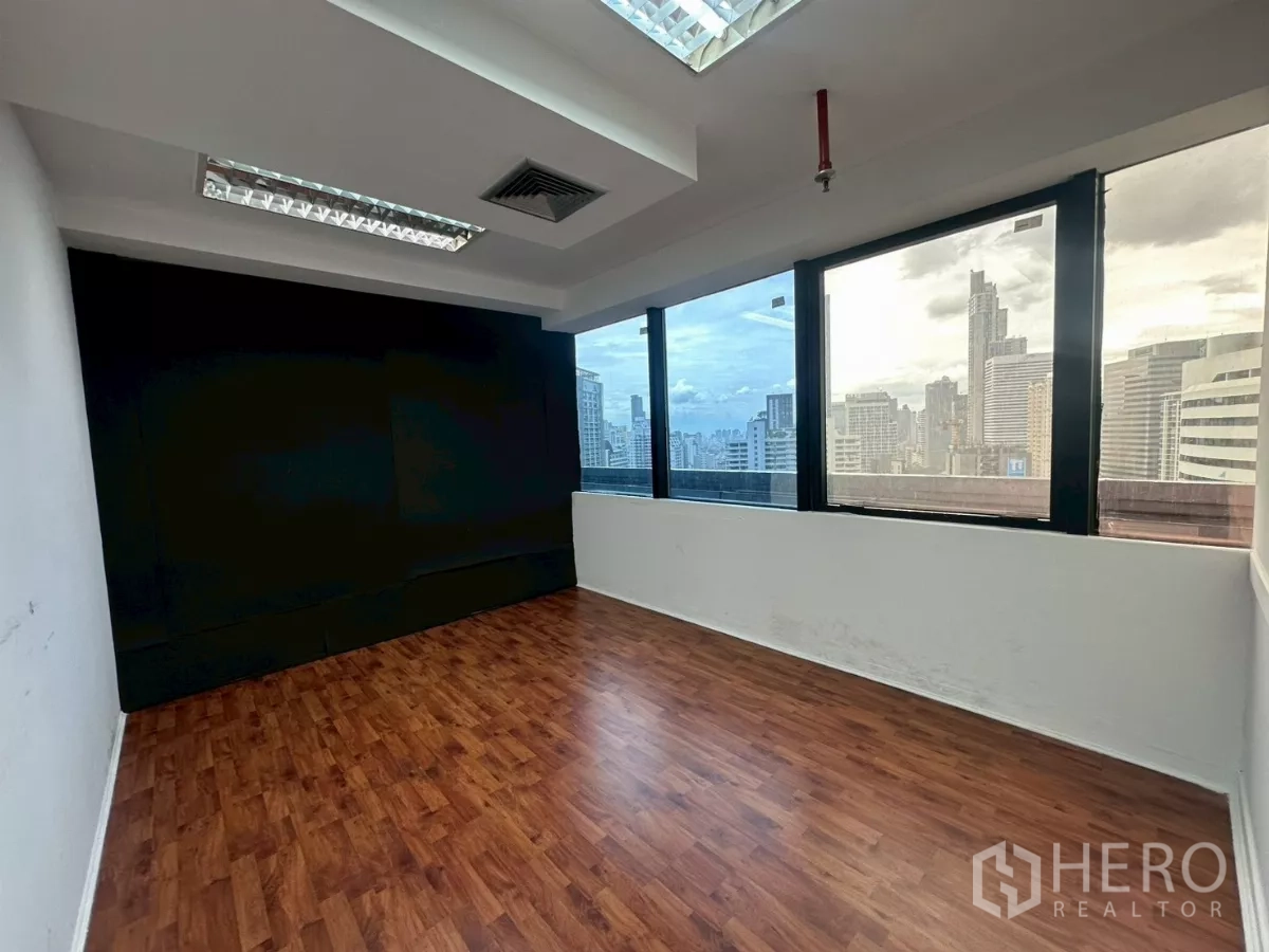 Office Space for rent in Khlong Toei, Bangkok - Corner office with panoramic city views through large windows and wood flooring.