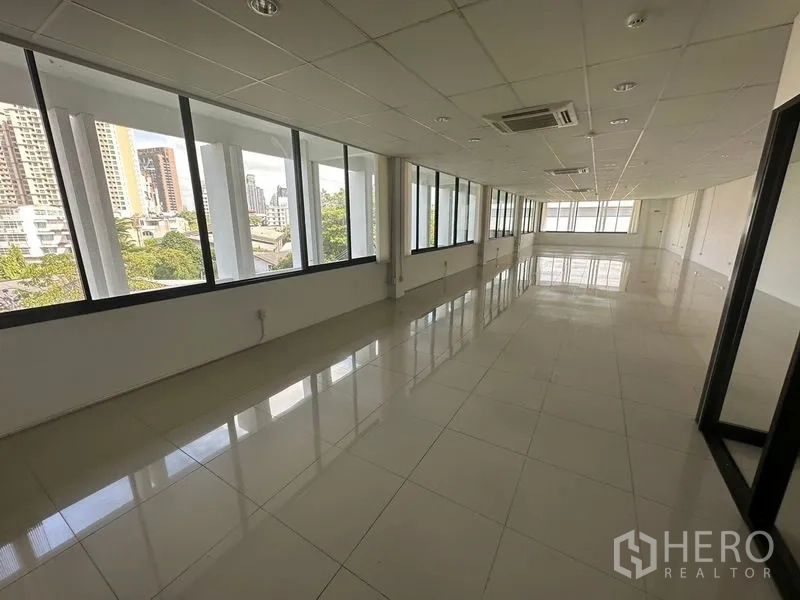 Office Space for rent - Spacious workspace corridor with panoramic windows and glossy tiles overlooking Sukhumvit skyline.