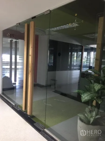 办公空间 出租在Bang Kapi, Bangkok - 现代办公室入口，落地玻璃双开门配木质把手与绿植，位于Bang Kapi。