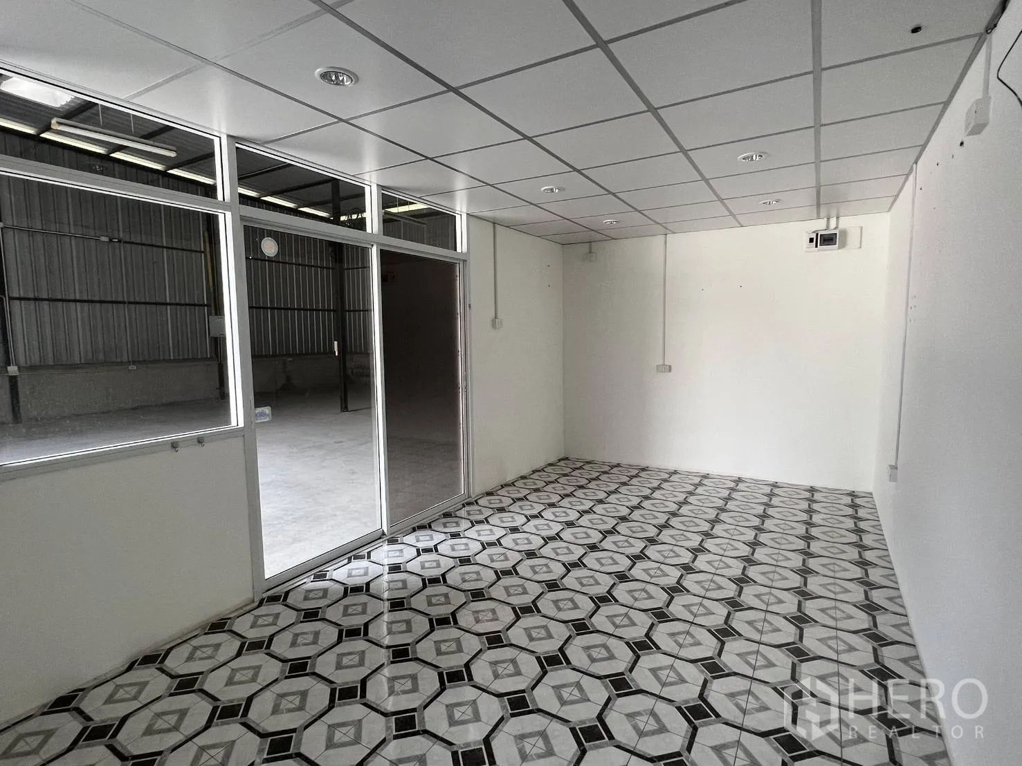 Warehouse for rent in Lat Krabang, Bangkok - Bright office room with drop ceiling and patterned tile floor facing the warehouse floor.