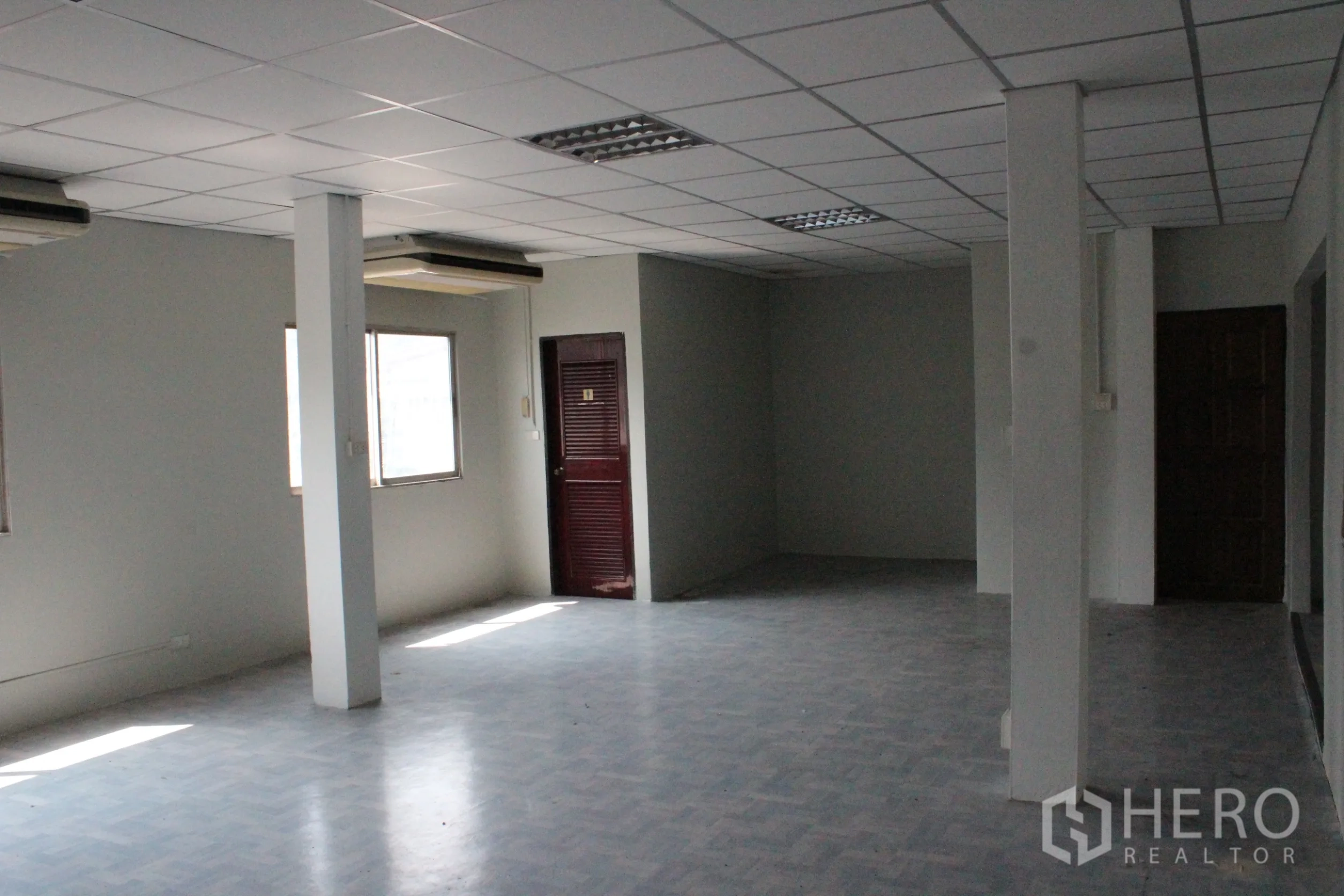 Home Office for rent in Khlong Toei, Bangkok - Bright flexible office space with windows, columns and a suspended ceiling.