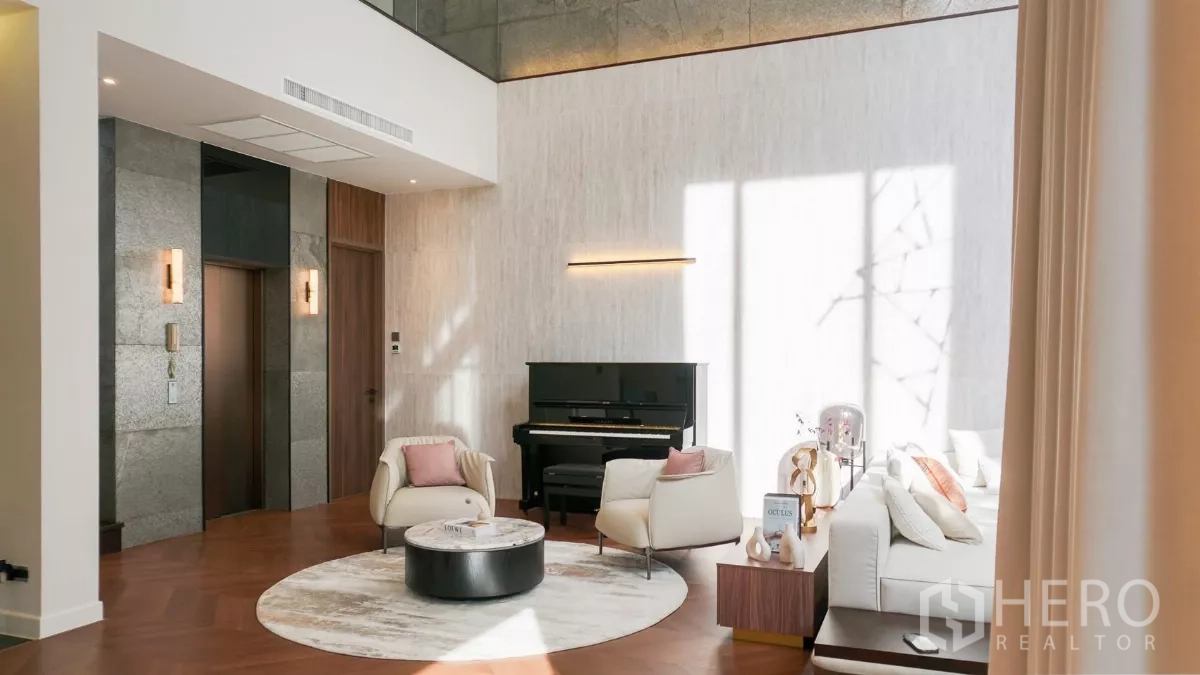 Detached House for rent or sale in Bang Kapi, Bangkok - Lounge corner with upright piano beside the home elevator and tall curtained windows.