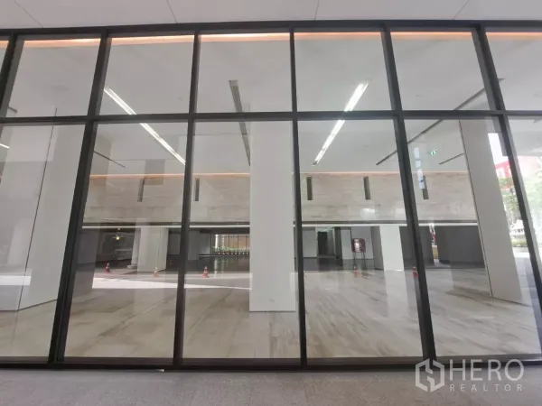 Retail Space for rent - Expansive glass storefront revealing a bright double-height interior with polished stone floors.
