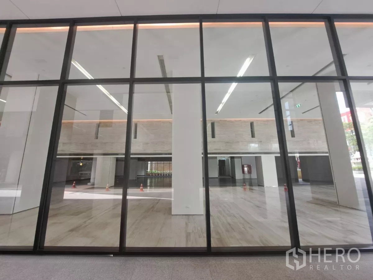 Retail Space for rent - Expansive glass storefront revealing a bright double-height interior with polished stone floors.