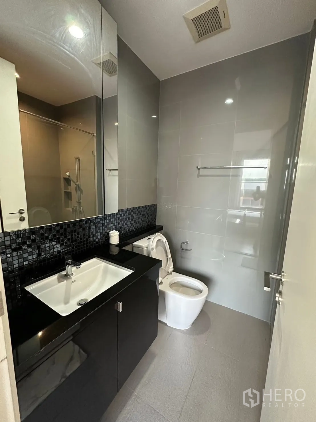 Condominium for rent or sale in Chatuchak, Bangkok - Second bathroom with large mirror, black countertop vanity, and toilet.